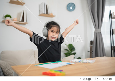 Happy Young Girl Enjoying Creative Activities at Home with Headphones and Bright Colors in a Cozy Living Room Setting 132938246