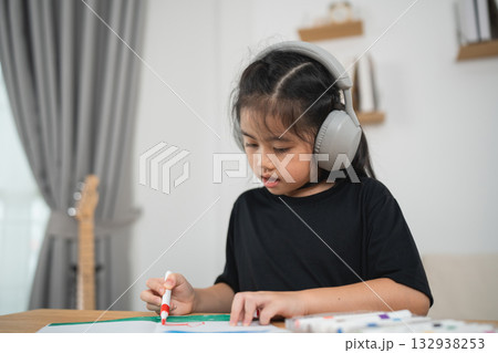 Young Girl with Headphones Engaged in Creative Drawing Activity in Cozy Indoor Environment Young Girl with Headphones Engaged in Creative Drawing Activity in Cozy Indoor Environment 132938253