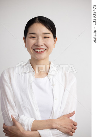 白い壁の前で腕を組み微笑むミドル女性 白い壁の前で腕を組み微笑むミドル女性 132938478