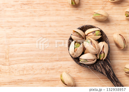 Roasted Pistachio nuts in a spoon on wooden background, Table top view Roasted Pistachio nuts in a spoon on wooden background, Table top view 132938957