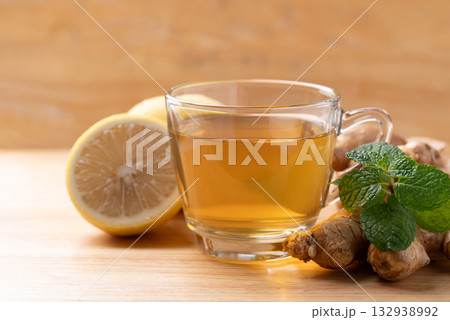 Lemon and ginger tea in cup glass with mint leaf, Healthy hot drink Lemon and ginger tea in cup glass with mint leaf, Healthy hot drink 132938992