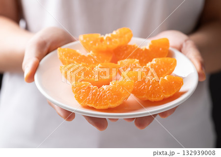 Fresh cut of Mandarin orange fruit on plate holding by hand ready to eating 132939008