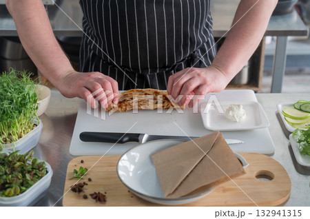 The chef prepares a flatbread with herbs. The chef prepares a flatbread with herbs. 132941315