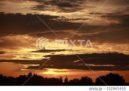 The sky is filled with clouds and the sun is setting 132941410