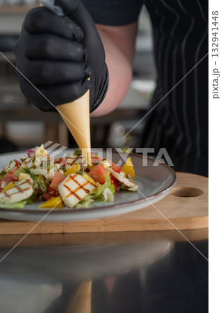 The chef seasons the salad with sauce.  132941448