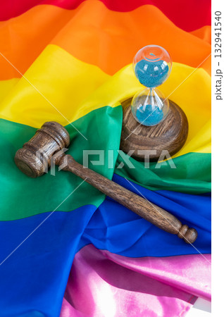 Judge's gavel and hourglass on rainbow flag. Judge's gavel and hourglass on rainbow flag. 132941540