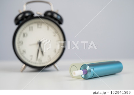 Electronic cigarette and alarm clock on white background. Tobacco heating systems. 132941599