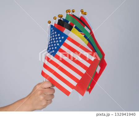 A woman's hand holding a bunch of small flags of different countries.  132941940