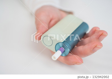 Woman holding electronic cigarette on white background. Tobacco heating systems. Woman holding electronic cigarette on white background. Tobacco heating systems. 132942002
