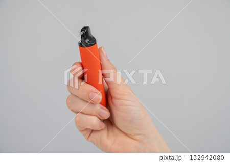 Woman holding disposable vape on white background. Copy space. Woman holding disposable vape on white background. Copy space. 132942080