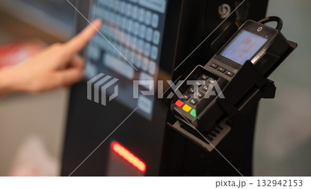 A woman uses a self-checkout machine. A woman uses a self-checkout machine. 132942153