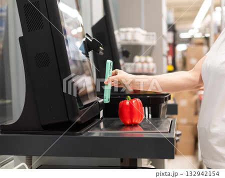 A woman buys bell peppers at a self-checkout. A woman buys bell peppers at a self-checkout. 132942154