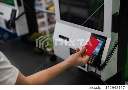 Woman paying with credit card at self-checkout.  132942167