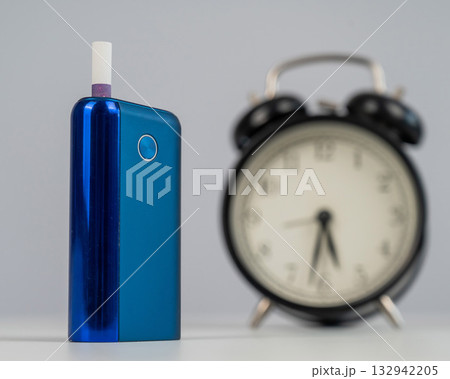Electronic cigarette and alarm clock on white background. Tobacco heating systems. 132942205