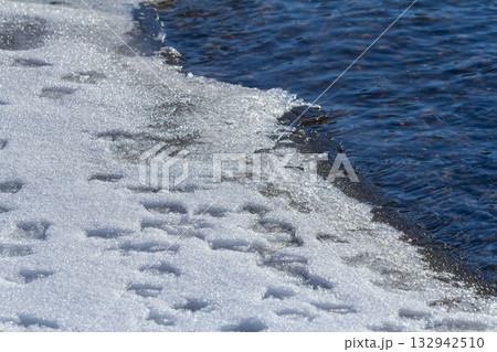 Ice meets water in a serene winter landscape during a bright sunny day by the river 132942510