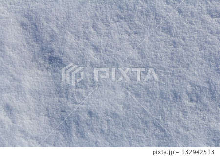 Snow-covered ground reveals a soft fluffy texture under bright sunlight on a winter day in a serene landscape 132942513