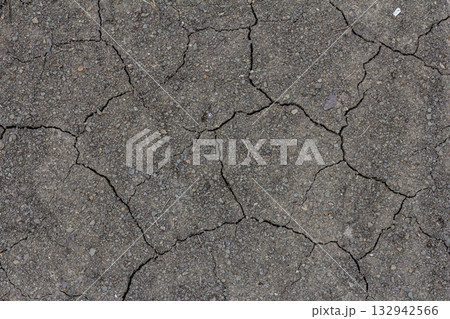Dry cracked earth showing signs of drought during summer in an arid landscape highlighting the effects of climate change on soil quality 132942566
