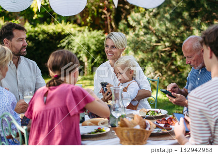 Family sharing food during garden grill party. Family sharing food during garden grill party. 132942988