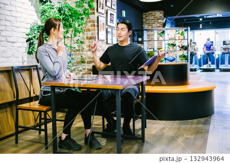 スポーツジムで入会案内を受ける女性 132943964