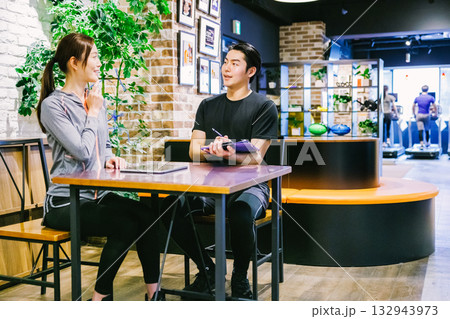 スポーツジムで入会案内を受ける女性 132943973