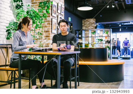 スポーツジムで入会案内を受ける女性 132943993