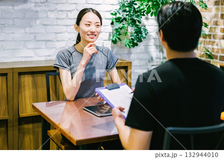 スポーツジムで入会案内を受ける女性 132944010