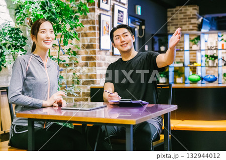 スポーツジムで入会案内を受ける女性 132944012