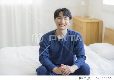 ベッドで伸びをする男性　 132945772