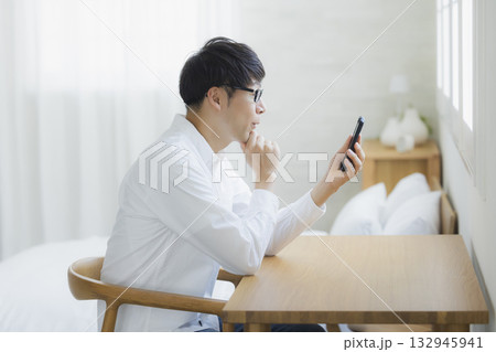 ベッドルームでスマホを見る男性 132945941