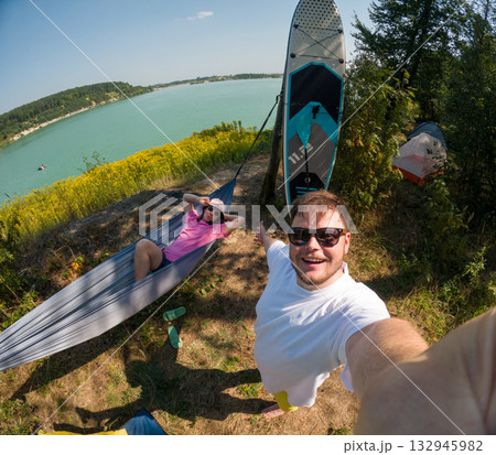 Couple Enjoying Lakeside Camping with Paddleboard 132945982