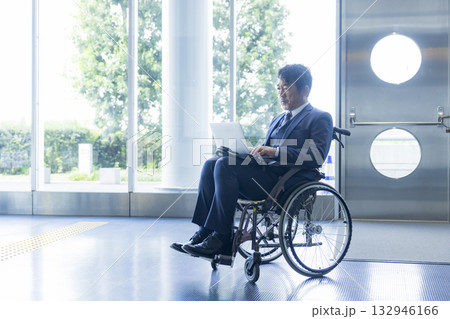 車椅子に乗るスーツの男性 132946166