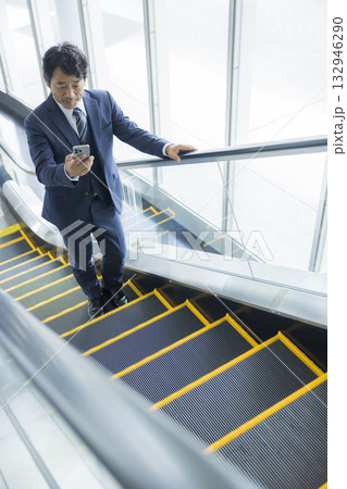 エスカレーターに乗るビジネスマン 132946290
