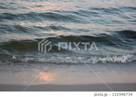 Sea wave washing sandy beach at sunset 132946734