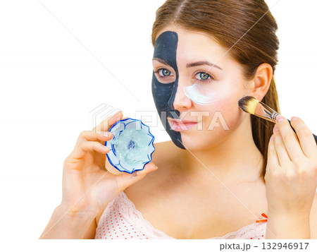 Girl black mask on half face apply white mud Girl black mask on half face apply white mud 132946917