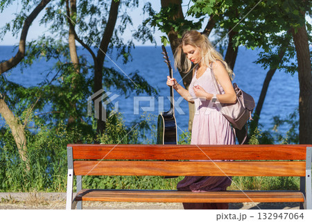Woman playing acoustic guitar in park 132947064