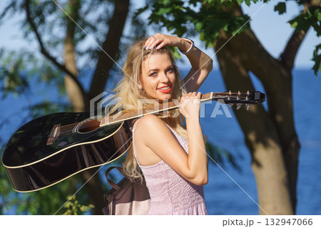 Woman playing acoustic guitar in park 132947066