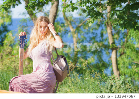 Woman playing acoustic guitar in park 132947067