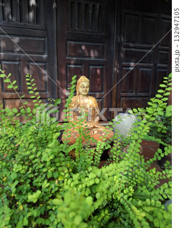 Terracotta Buddha statue among green plants 132947105