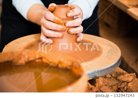 Hands of professional potter molding clay on pottery wheel 132947243
