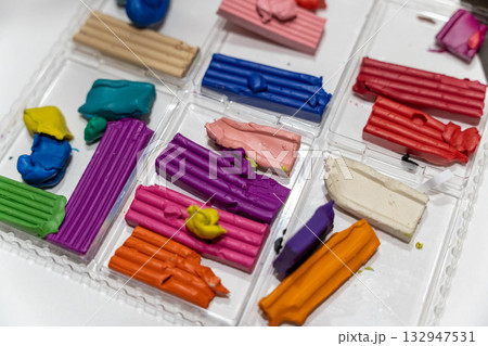 Colorful modeling clay pieces arranged in a clear plastic container, showcasing various vibrant hues and textures, ideal for creative projects and artistic endeavors Colorful modeling clay pieces arranged in a clear plastic container, showcasing various vibrant hues and textures, ideal for creative projects and artistic endeavors 132947531