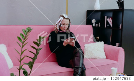 Woman with foil in her hair using smartphone while waiting for hair color to process in contemporary salon 132947658