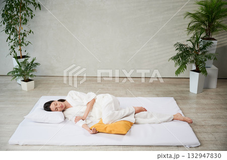 Beautiful woman relaxing after Thai massage, lying on mat with closed eyes. Beautiful woman relaxing after Thai massage, lying on mat with closed eyes. 132947830
