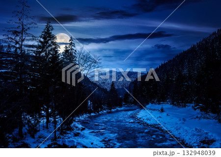 freezing river winding among coniferous forest at night. snow on the ground in countryside valley in full moon light. background for investment or abstract concepts 132948039
