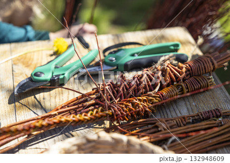 Weaving willow branches with tools for traditional craft 132948609
