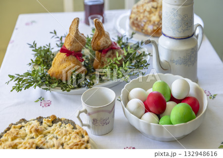 Easter holiday table setting with bunny bread and colored eggs Easter holiday table setting with bunny bread and colored eggs 132948616