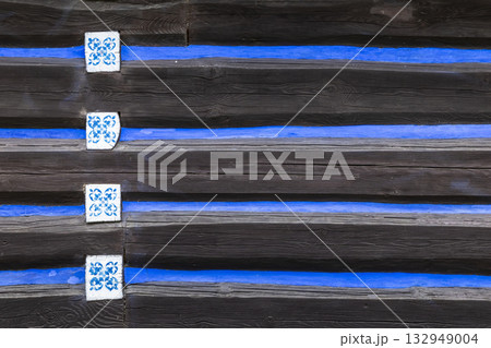 Old wooden log wall with blue pattern tiles in Osturna 132949004