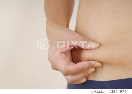 皮下脂肪を指でつまむ中年男性のお腹 132949744