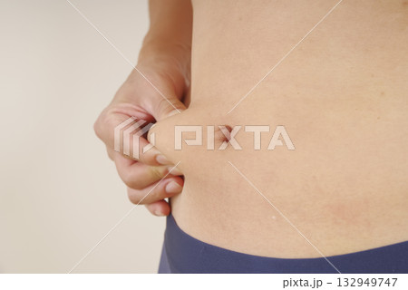 皮下脂肪を指でつまむ中年男性のお腹 132949747