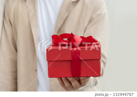 Red gift box with bow-knot in mans hand. Present with love for Birthday or Valentine's Day. Greeting card. Close up Red gift box with bow-knot in mans hand. Present with love for Birthday or Valentine's Day. Greeting card. Close up 132949787