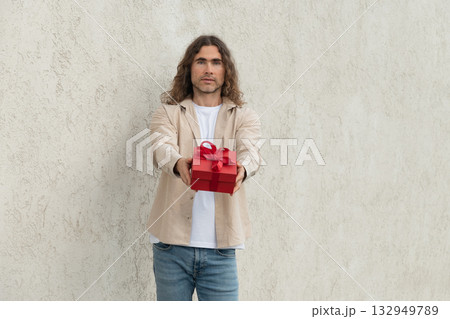 Happy handsome caucasian man giving red gift box with love. Birthday. Romantic surprise and celebration. Greeting card. Happy handsome caucasian man giving red gift box with love. Birthday. Romantic surprise and celebration. Greeting card. 132949789